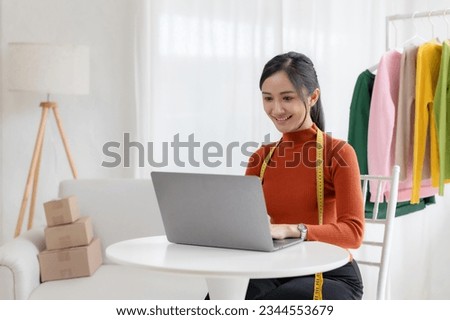 Beautiful Asian online business owner who sell cloth online and explain the feature, prices and characteristic of the product using a laptop.