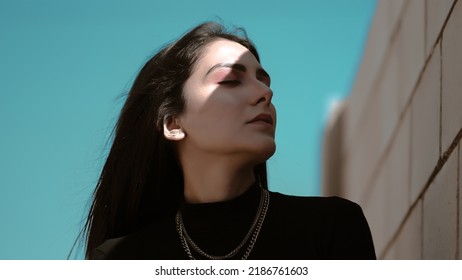 Beautiful Asian Pakistani Girl Posing. Woman With Brown Hair, In Black Dress, Glowing Skin. Attractive, Sexy Fashion Model. Fashion Shot Outdoor, On Block Background. Hands Posing, Make Up
