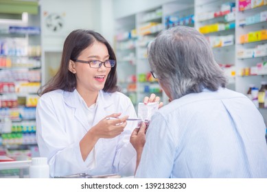 Beautiful asian Pharmacist explaining the pills to patient in drug store
