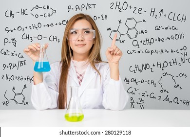 Beautiful Asian scientific researcher holding a liquid solution with science or chemistry formula
