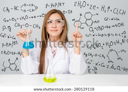 Beautiful Asian scientific researcher holding a liquid solution with science or chemistry formula
