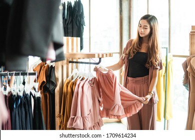 beautiful asian shopping woman looking at some clothes in the store