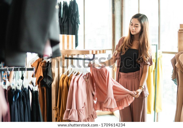 beautiful asian shopping woman looking at some\
clothes in the store