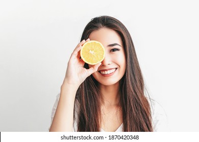 Beautiful Asian smiling brunette girl with an fruit orange in her hands on a white background. Selective focus