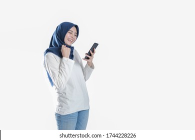Beautiful Asian student in hijab excited while holding a mobile phone