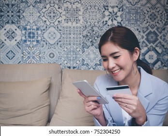 Beautiful Asian using her mobile to do internet banking, online shopping while she holding credit card in another hand. Paypal concept. Internet Banking concept.