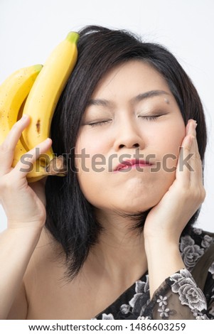 Beautiful Asian woman with bananas fruit. Tropical fruit Dessert Health Nutrition vegetarian concept. Fashion posture. Disappointing expression Worried Not satisfied and unhappy emotion.