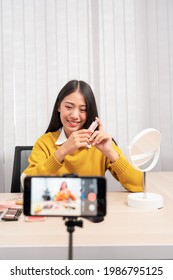 Beautiful Asian Woman Blogger Using Camera Phone Recording Vlog Video Live Streaming And Applying Makeup For Review Cosmetics At Home.