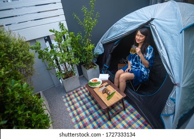 A Beautiful Asian Woman Camping At The Backyard With Alas Of Beer , Beef Steak And A Favorite Book For Social Distancing During The Quarantine Time Because The Covid-19 Outbreak.