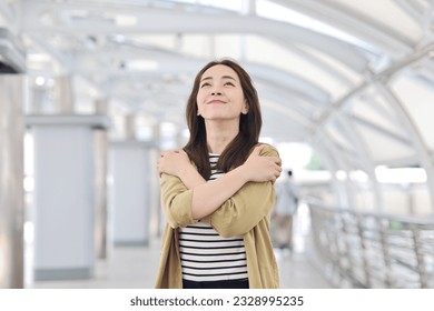 Beautiful Asian woman in casual style standing hugging herself ,Positive self love and self care concept.