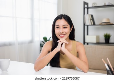 Beautiful Asian Woman Chatting Video Conference Online Looking At Camera Sitting In Living Room At Home. Business Woman Looking At Screen Meeting On Social Media. Work From Home.