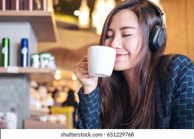 A Beautiful Asian Woman Close Her Eyes And Listening To Music With Headphone While Drinking Coffee With Feeling Happy And Relax In Modern Cafe