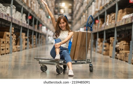 Beautiful Asian Woman Customer  Pushing Trolley Or Pick Up Goods Put In Cart In Warehouse Store.Self Service Shopping Concept