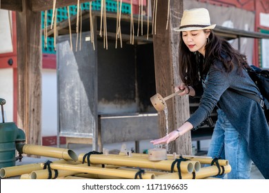 beautiful asian woman doing hands washing in japanese shrine for purifying her soul.