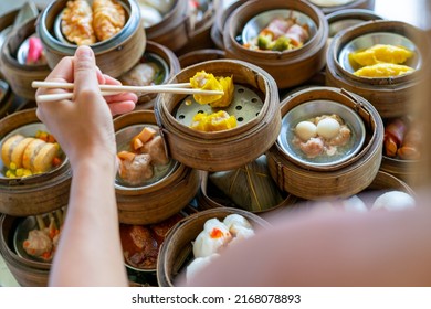 Beautiful Asian woman eating Chinese food steamed dumpling in bamboo steamer with chopsticks in Chinese restaurant. Happy female tourist enjoy eating and travel on summer holiday vacation. - Shutterstock ID 2168078893