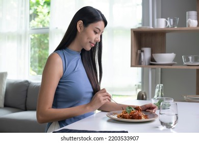 Beautiful Asian Woman Eating Pasta On Table In The Morning At Home. Smiling Healthy Woman Eating Spaghetti While Sitting And Having Breakfast At The Kitchen Table.