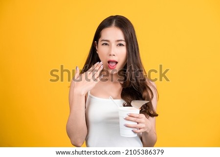 Beautiful Asian woman eating spicy instant noodles. She shows signs of being spicy.