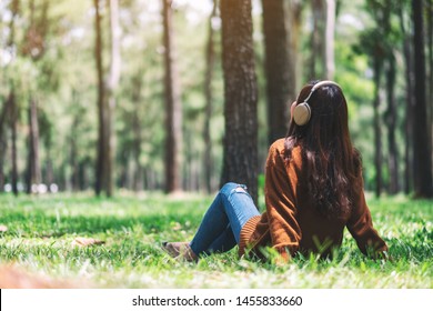 A beautiful asian woman enjoy listening to music with headphone with feeling happy and relaxed in the park - Powered by Shutterstock