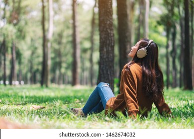 A beautiful asian woman enjoy listening to music with headphone with feeling happy and relaxed in the park - Powered by Shutterstock