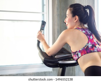 Beautiful Asian Woman Exercising In The Gym Fitness Use Spinner Bike Looking Outside Copy Space