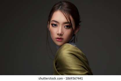 Beautiful Asian woman in a green shawl. Beauty of mysterious Chinese girl with flowing hair. Fashion, clothing and cosmetics
