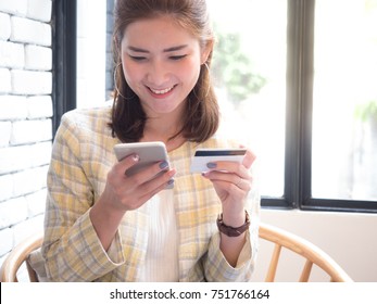 beautiful asian woman holding mobile and credit card in her hands with smiley face. Online shopping concept. 