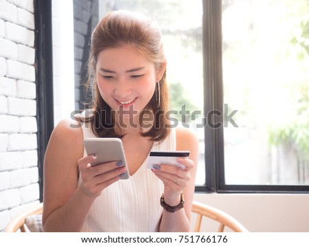 beautiful asian woman holding mobile and credit card in her hands with smiley face. Online shopping concept. 