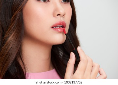 Beautiful Asian Woman Holding Red Lipgloss And Applying It