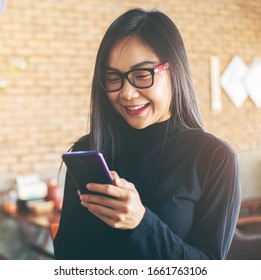 Beautiful Asian Woman Holding Smart Phone For Social Networks, Online Shopping, Transfer Money, Sending Messages, In The Coffee Shop.