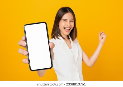 Beautiful Asian woman holding smartphone mockup of blank screen and smiling on yellow background.