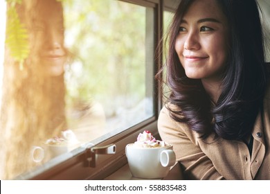 A beautiful asian woman and hot coffee with whipped cream topping in the cafe , feeling happy and smiley face