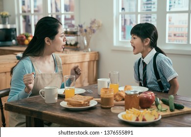 Beautiful Asian Woman Housewife With Bad Little Girl Daughter Screaming At Each Other. Concept Of Family Conflict. Angry Mom And Kid In Uniform Argue In Breakfast Time In Morning Before School.