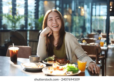 Beautiful Asian woman joyful eating a meal in restaurant. - Powered by Shutterstock