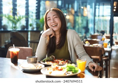 Beautiful Asian woman joyful eating a meal in restaurant. - Powered by Shutterstock