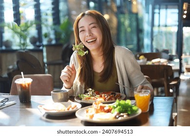 Beautiful Asian woman joyful eating a meal in restaurant. - Powered by Shutterstock