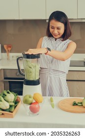 Beautiful Asian Woman Juicing Making Green Juice With Juice Machine In Home Kitchen. Healthy Concept.