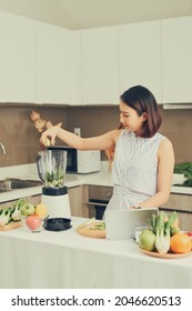 Beautiful Asian Woman Juicing Making Green Juice With Juice Machine In Home Kitchen. Healthy Concept.