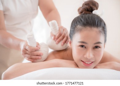 A beautiful Asian woman is laid back and relaxing, the masseuse uses a hot herbal compress in a spa shop