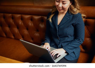 Beautiful Asian woman with laptop sitting in a cafe and smiling	