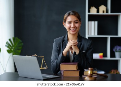 Beautiful Asian Woman Lawyer Sitting At A Table Smiling Happy With A Laptop Computer With Law Books Hammer And Scales Hammer And Scale.