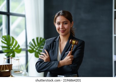 Beautiful Asian Woman Lawyer Sitting At A Table Smiling Happy With A Laptop Computer With Law Books Hammer And Scales Hammer And Scale.