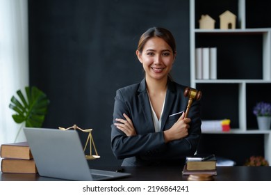 Beautiful Asian Woman Lawyer Sitting At A Table Smiling Happy With A Laptop Computer With Law Books Hammer And Scales Hammer And Scale.