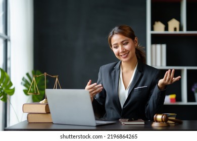 Beautiful Asian Woman Lawyer Sitting At A Table Smiling Happy With A Laptop Computer With Law Books Hammer And Scales Hammer And Scale.