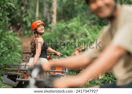beautiful asian woman looking back to the camera while riding the atv at amusement park