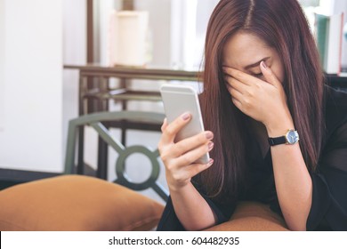 A Beautiful Asian Woman Looking At Smart Phone With Feeling Sad In Modern Cafe