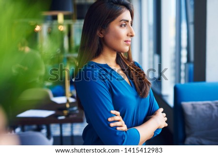 Beautiful Asian woman looking through window in the office
