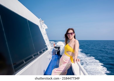A beautiful, Asian woman on a boat and enjoys the calm sea during her summer holidays. Luxury yacht woman enjoying freedom on deck in the wind relaxing. summer vacation trip.Summer, sea, vacation.