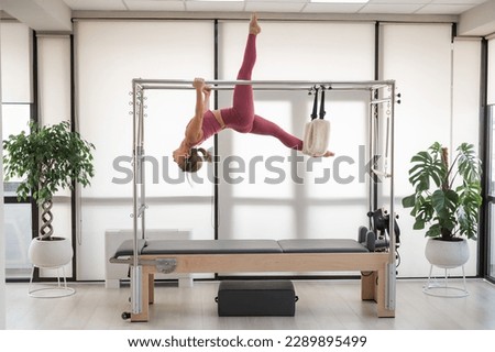 Beautiful asian woman in pink sportswear doing pilates on bed reformer. 
