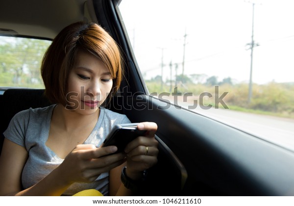 Beautiful\
asian woman play mobile phone while travel in car. Technology cell\
phone isolation. Internet and social\
media
