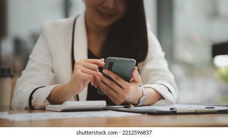 Beautiful Asian Woman Playing Mobile Phone In Her Break From Work, She Is A Marketing Manager Of A Startup Company, Female Leader, Supervisor, Ceo. Female Leadership Concept.